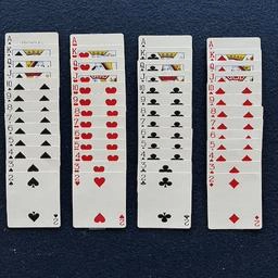 Photo of deck of cards face up in four neatly organized and sorted columns on green felt table